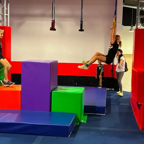 Girl swinging from rope over colored blocks