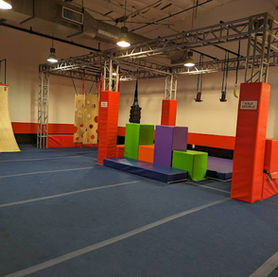 Open floor ninja training zone with warped wall and foam equipment in San Mateo, CA